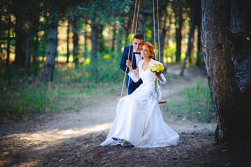 Fototapeta premium Young beautiful couple in a blue suit and white wedding dress with a bouquet