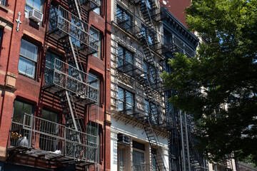 Fototapeta na wymiar Row of Beautiful Old and Colorful Brick Apartment Buildings with Fire Escapes in SoHo of New York City