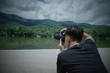 Over shoulder  view point of young man traveller using his camera