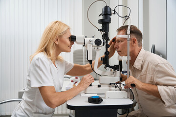 Fototapeta na wymiar Physician examining the eyeball of patient in cabinet