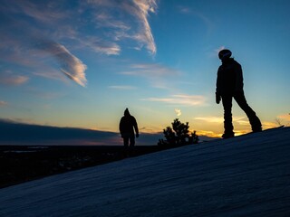 silhouette of couple snowboarding at sunset