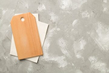 Cutting board with towel on concrete background, top view