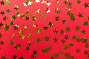 Golden confetti stars on color background, top view