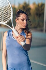 Vertical shot of a young attractive fit caucasian female posing with a tennis racket on a court