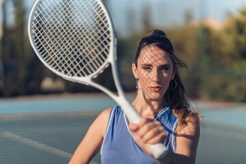 Young attractive fit caucasian female posing with a tennis racket on a court