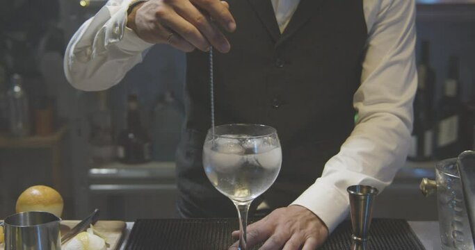 Young barman in a white shirt and black apron making cocktail at party in nightclub with colorful lights - Shot on RED camera - High quality photo