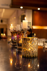 Velas en candelabros de cristal sobre mesa con fondo desenfocado. Paleta de colores cálida.