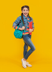 Surprised girl back to school. Teenage girl holding school books yellow background. School education