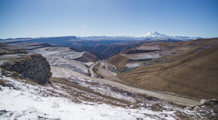 View of the mountain range and hills with snow in November in sunny weather, hills in the mountains with snow and Mount Elbrus