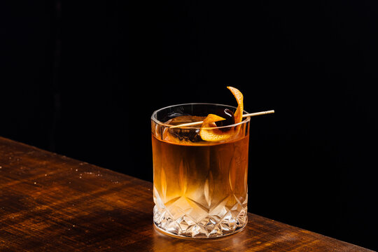 old fashioned cocktail on a wooden table and black background