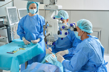 Close up photo of medical workers doing eye microsurgery