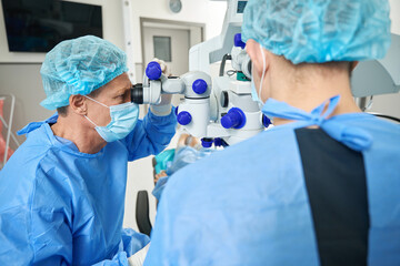 Medical worker and intern doing laser vision correction operation