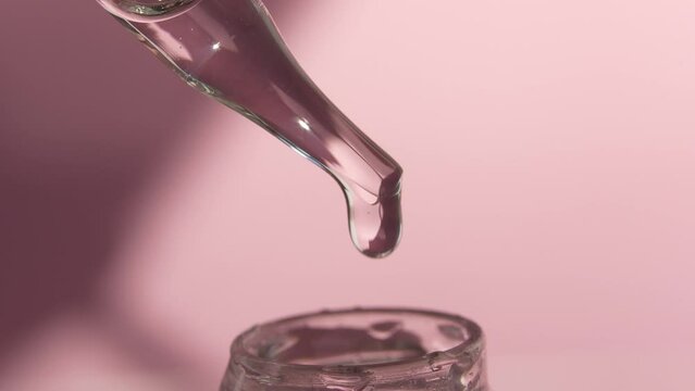 Pipette with liquid essence on a light pink background. Serum for the face. The concept of an extract for cosmetic purposes. High quality video
