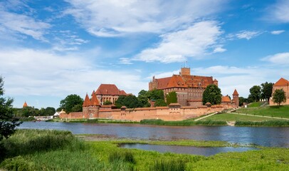 Naklejka na ściany i meble Landscape of Malbork castle with Nogat river and unrecognizable tourists