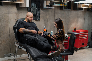 Woman tattoo artist makes a tattoo to a man on his arm, tattoo studio