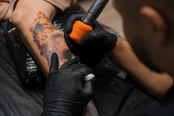 Fototapeta na wymiar Close-up - the process of tattooing a woman on her leg. Male tattoo artist making a tattoo