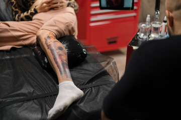 Tattoo with an alien on the leg of a woman during a tattoo correction session in a tattoo studio