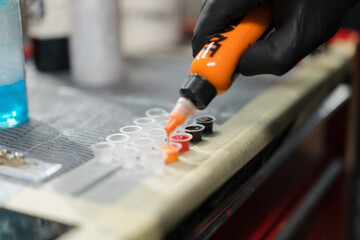 Fototapeta premium The process of pouring tattoo ink into a container, tattoo studio. Tattoo artist in studio preparing