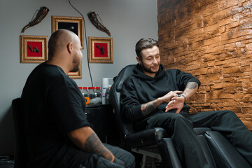 Fototapeta na wymiar Interior of a tattoo studio - a man shows his tattoos to a master tattoo artist
