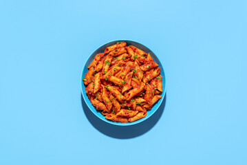Penne pasta in tomato sauce, top view on a blue background