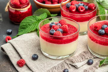 Raspberry Panna cotta with raspberry jelly on a dark background. Berry dessert with cream sauce in small jars. place for text