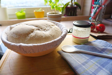 sour dough bread raw in fermentation basket with starter on kitchen table