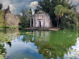 Fototapeta na wymiar Ruins of a temple in the middle of a lake at the English Garden of Caserta Royal Palace, Italy.