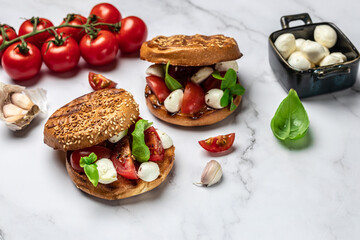 Open sandwiches with cherry tomatoes, mini mozzarella, fresh basil leaves, caprese on bread, Traditional italian appetizer or snack, antipasto. banner, menu, recipe place for text, top view