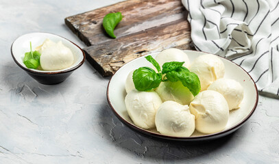 Cheese collection, white balls of soft Italian cheese mozzarella, served with fresh basil leaves on...