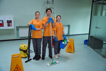 Young professional cleaners holding tools and equipment and standing together