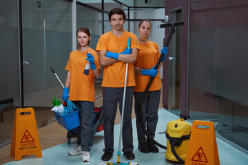 Efficient cleaners standing together with professional equipment in hands