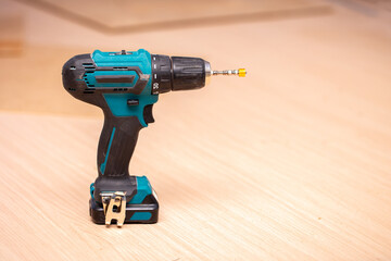 Electric cordless drill driver on the background of a carpentry shop, a professional tool for home repair, a hand power tool, copy space.