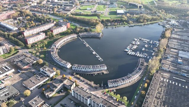 Harbour of Weesp, Aquamarin around the former industrial harbor. Suburban residential real estate housing in the shape of a circle. Small port recreactional living along the water. Aerial.