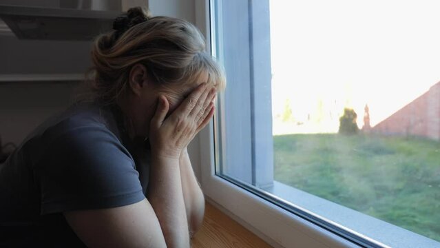 Upset depressed mature woman crying alone at home thinking of loneliness or grief, sad middle aged senior woman in tears worried about health problems mourning feeling lonely miserable concept