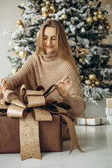 Woman at home by the christmas tree with presents
