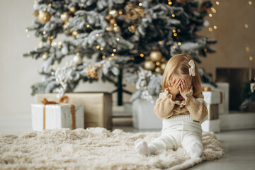 Cute baby girl sitting by the christmas tree