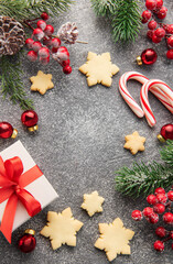 Christmas background with gingerbread cookies, gift boxe and fir branches  on darck concrete background.