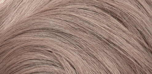 Blond hair close-up as a background. Women's long light brown hair. Beautifully styled wavy shiny...