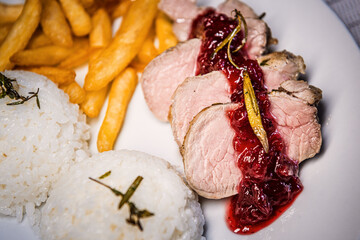 Baked pork tenderloin with cranberry sauce, rice and fries