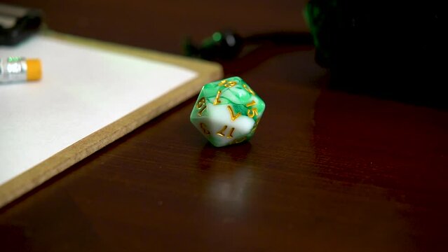 Green 20 sided dice dropping on a table.