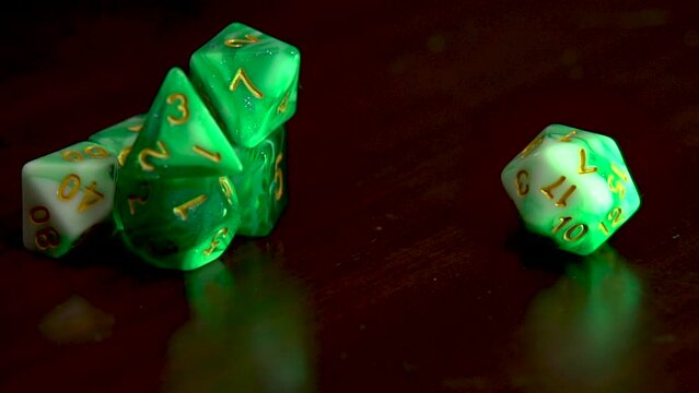 Hand spinning a green sided dice into view.