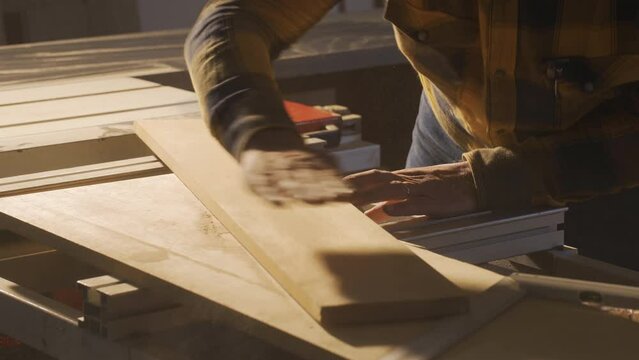 Measuring wood with meter in carpentry shop.
Male carpenter measuring dusty wood with meter and marking with pencil in shop.
