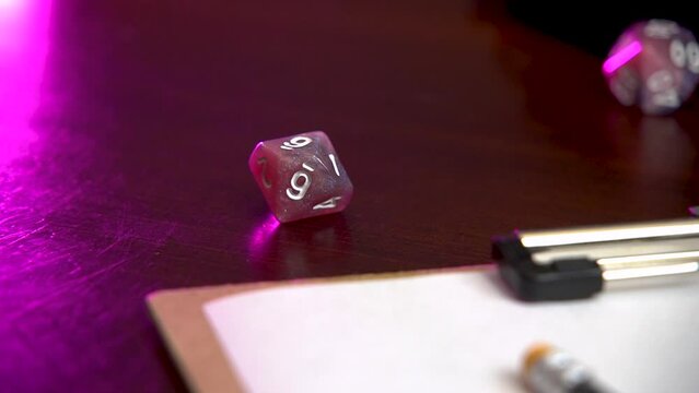 Rolling a pink 10 sided dice into view.