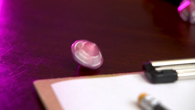 A hand spins a pink 10 sided dice.