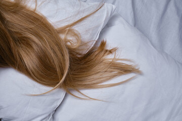 Woman sleeps in bed. A girl with blond hair under a blanket on a pillow. Get up. Dream. Happy morning in the bedroom. Cozy and comfortable. Pillow blanket. Recovery, rest, lifestyle