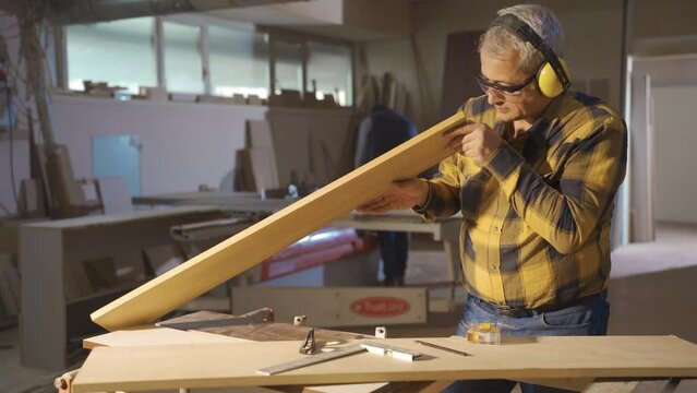 Carpentry Workshop.
The carpenter takes measurements from wood with a meter.
