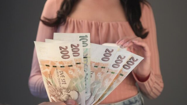 woman takes out a czech republic banknote of 500 CZK koruna from a fan of banknotes. Finance concept