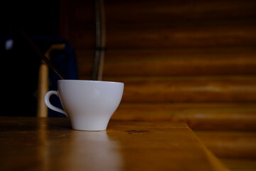 A white cup stands on a wooden table