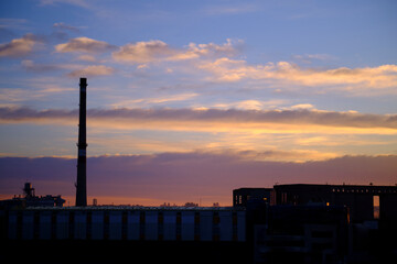 Silhouette of a broken forgotten factory on the background of sunset or sunrise