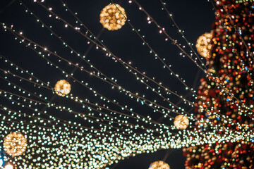 Blurred festive Christmas tree lights and golden illuminated balls at night. New Year holidays celebration background